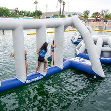 Inflatable water park structure with people on it, branded 'Aquaglide', in a body of water.