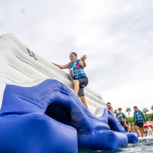 Person on an inflatable water slide with others in the background
