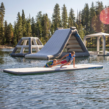 Two children playing on an Aquaglide Full Deck 15.0 in a lake with trees in the background