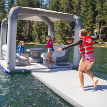 Inflatable floating dock with children playing on a lake surrounded by trees