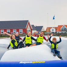 Children on an inflatable water slide with houses in the background