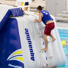 Person climbing onto an inflatable water toy labeled 'Aquaglide' in a pool.