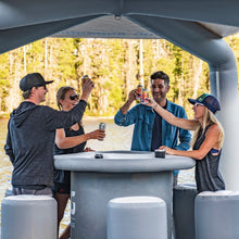 Group of people enjoying drinks on a Aquaglide OG Lounge with trees in the background
