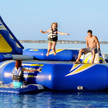 People on an inflatable water park structure in a body of water with a clear sky.