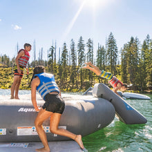 Three people wearing life jackets play on Aquaglide Recoil Tramp 14.0 