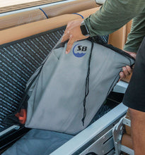 A person inside a boat or vessel storage compartment is placing or retrieving a Island Hopper Inflatable Bull Shark Bumper Fender
