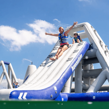 Inflatable water slide with a person at the top against a blue sky