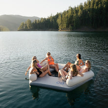 Group of people on Aquaglide Lazy Lounge in a lake with mountains and trees in the background
