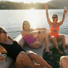 Three women enjoying a sunny day on a lake, sitting on Aquaglide Lazy Lounge