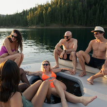 Group of people sitting on Lazy Lounge in a lake with trees in the background