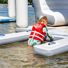 Child in a life jacket on an inflatable raft in water with other rafts in the background.