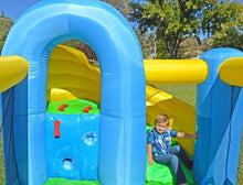 Child playing in Island Hopper Curved Double Slide with green grass and trees in the background.