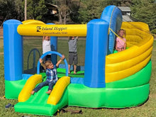 Children playing on an inflatable Island Hopper double slide in a grassy area.