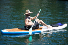 A man wearing a straw hat sits on a Island Hopper Inflatable Sport Board 